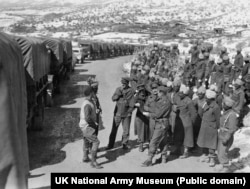 Советские солдаты и военнослужащие Британской индийской армии в Иране на фоне колонны американских грузовиков, следующих в СССР в рамках ленд-лиза, 1944 год