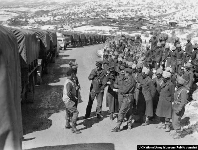 Советские солдаты и военнослужащие Британской индийской армии в Иране на фоне колонны американских грузовиков, следующих в СССР в рамках ленд-лиза, 1944 год
