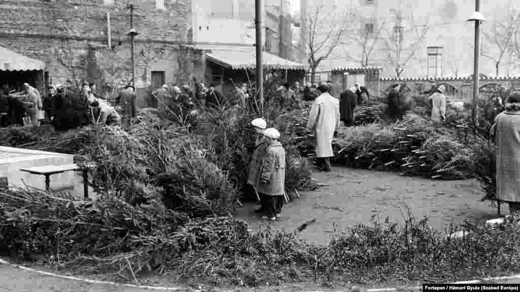 Karácsonyfavásár a&nbsp;Kálvin tér és a Kecskeméti utca sarkán álló Városkapu vendéglő kerthelyiségében 1957 telén Budapesten.&nbsp;Háttérben a Kecskeméti utca, középen a Magyar utca torkolata. Balra a tűzfalon az egykori városkapu emlékét idézi a téglából kirakott ábrázolás