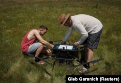 Angajați ai companiei ucrainene de drone Swarmer pregătesc un quadcopter cu inteligență artificială pentru zbor în regiunea Kiev, în iunie 2024.