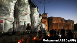 Ljudi stoje pored kamiona sa humanitarnom pomoći koji ulaze u pojas Gaze preko prelaza Rafa sa Egiptom, nekoliko sati nakon početka četvorodnevnog primirja u borbama između Izraela i Hamasa, 24. novembra 2023.