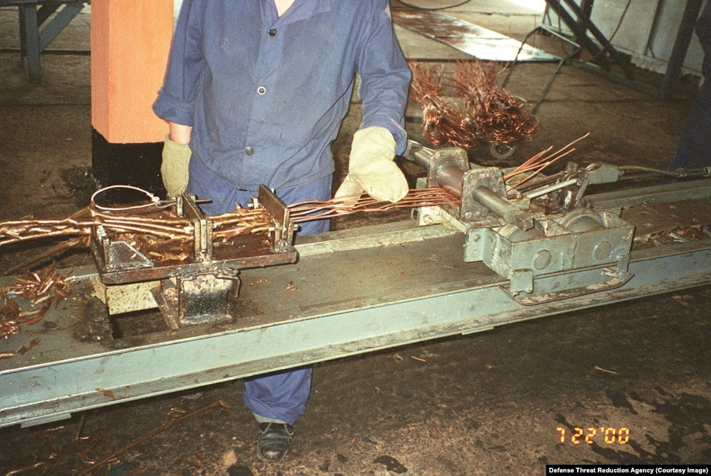 Një punonjës me tela bakri në një fotografi të përshkruar si “projekti i çmontimit të raketave”.