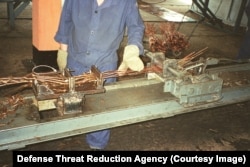 Radnik s dugim bakrenim žicama na fotografiji s oznakom "projekat demontaže silosa".
