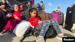 Copii palestinieni cu dublă cetățenie așteaptă la punctul de trecere a frontierei Rafah cu Egiptul să poată pleca din Gaza, pe fundalul războiului dintre Israel și grupul islamist Hamas. Rafah, în sudul Fâșiei Gaza, 1 noiembrie 2023.