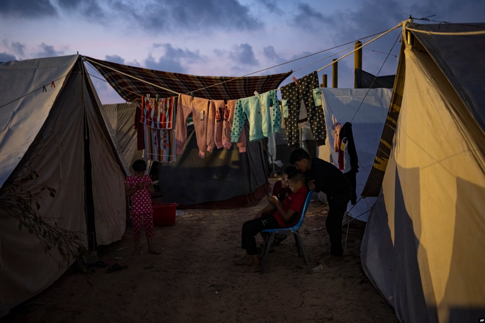 Fëmijët palestinezë, që u zhvendosën nga bombardimet izraelite në veri të Rripit të Gazës, duke shikuar në një telefon në një kamp në Han Junis, më 1 nëntor 2023.