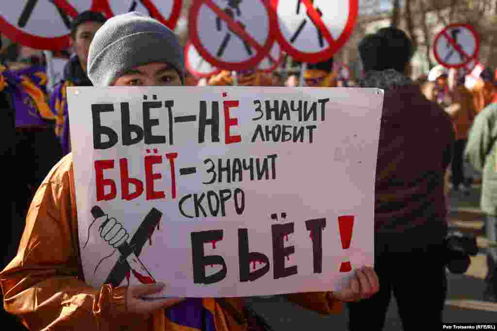 A man peers above a sign that says, &quot;If he beats you, it doesn&#39;t mean that he loves you. It means he is going to kill you.&quot; &nbsp;