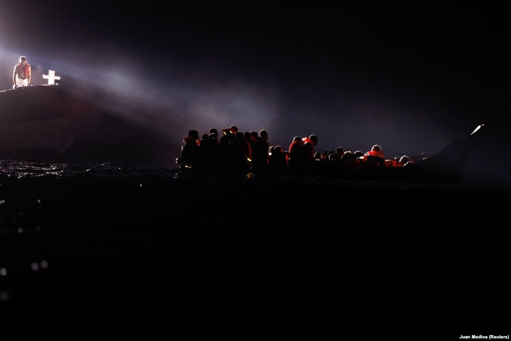 Emigrantët marrin udhëzime nga anëtarët italianë të Rojës bregdetare (Guardia Costiera) pranë anijes së shpëtimit Astral, të OJQ-së Open Arms në ujërat ndërkombëtare në jug të Lampedusës, në Detin Mesdhe, natën e 10 gushtit 2024. 