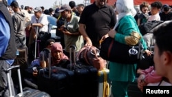 Kettős állampolgárságú palesztinok várakoznak az Egyiptommal közös rafahi határátkelőnél 2023. október 16-án