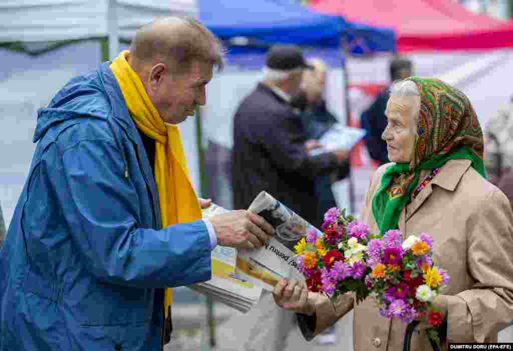 An elderly woman receives an electoral newspaper on the main street of Chisinau as Moldovans go to the polls in mayoral and local elections on November 5.