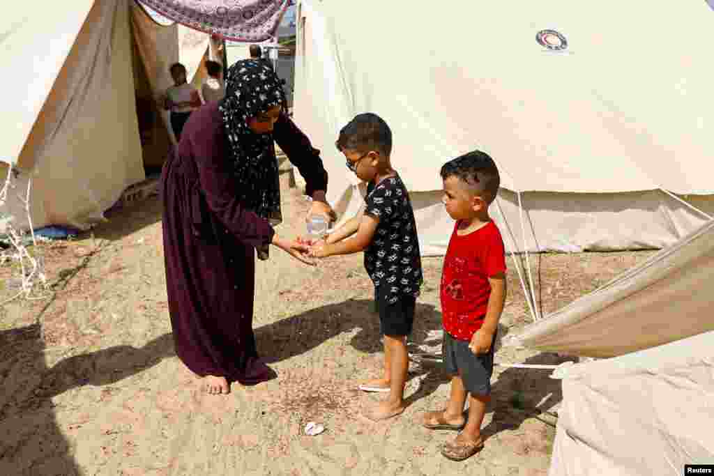 Një grua lan duart e një fëmije, ndërsa palestinezët, të cilët u larguan nga shtëpitë e tyre mes sulmeve izraelite, strehohen në kampin me tenda në një qendër të drejtuar nga Kombet e Bashkuara në Han Junis në Rripin e Gazës, më 23 tetor 2023.