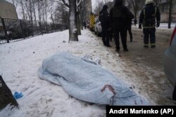 Telo pokriveno ćebetom leži na zemlji nakon ruskog raketnog napada na Harkiv, Ukrajina, 23. 1. 2024.