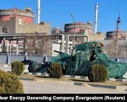 На фото, опубликованном 16 марта 2022 года, изображен российский танк, покрытый защитного цвета сеткой, у Запорожской атомной электростанции
