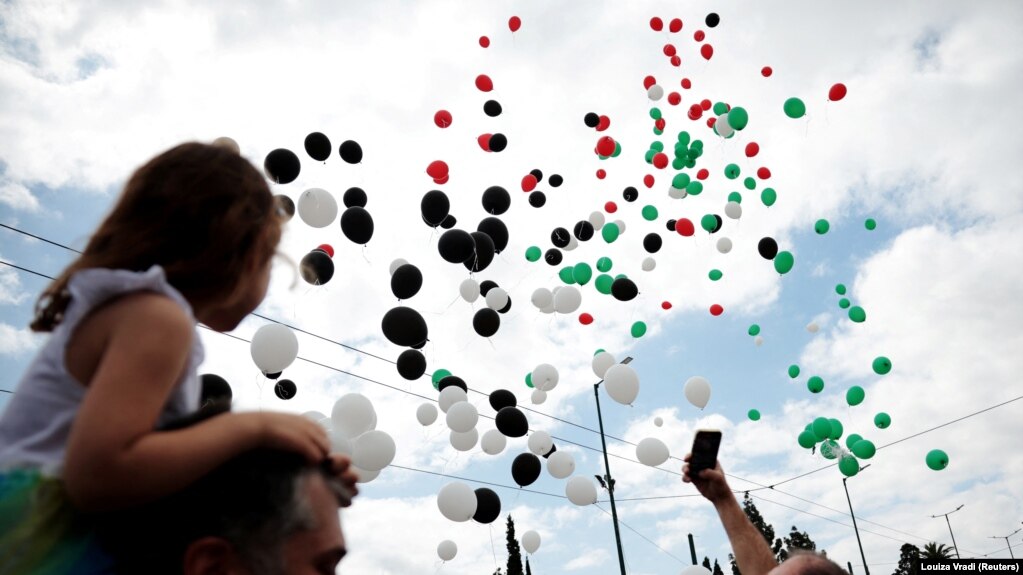 Demonstranti gledaju balone sa bojama palestinske zastave tokom marša povodom Međunarodnog dana radnika u Atini, Grčka, 1. maja 2024.
