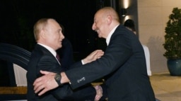 Azerbaijani President Ilham Aliyev (right) greets his Russian counterpart in Baku on August 17.