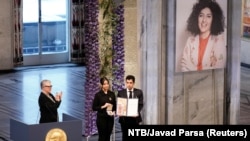 Narges Mohammadi's children hold the Nobel Peace Prize award, accepting it on behalf of their mother at Oslo City Hall on December 10.