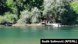 Police and rescuers work on the banks of the Drina River, near Tegare on the Bosnian side, where the migrant boat capsized, on August 22.