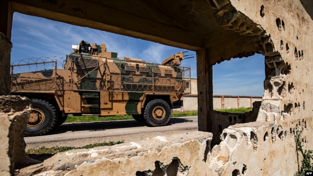 An army vehicle drives past the ruins of a building during a Turkish and Russian military patrol in the countryside of Rumaylan in Syria's northeastern Hasakeh Province bordering Turkey, on April 27.