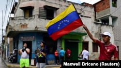 Një burrë valëvit flamurin venezuelas gjatë protestave pas rezultatit të kontestuar zgjedhor, 29 korrik, Karakas, Venezuelë.