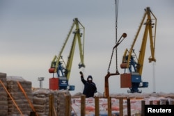 Radnici istovaruju građevinski materijal s teretnog broda u luci Mariupolj u Ukrajini pod ruskom okupacijom u oktobru 2023.