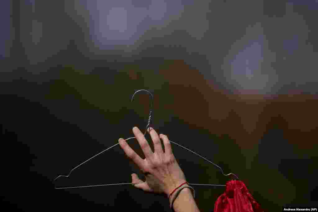 A woman holds a coat hanger symbolizing unsafe, illegal abortions as she takes part in a rally to raise awareness of the difficulties of getting an abortion in a state hospital outside the government headquarters in Bucharest on March 8.