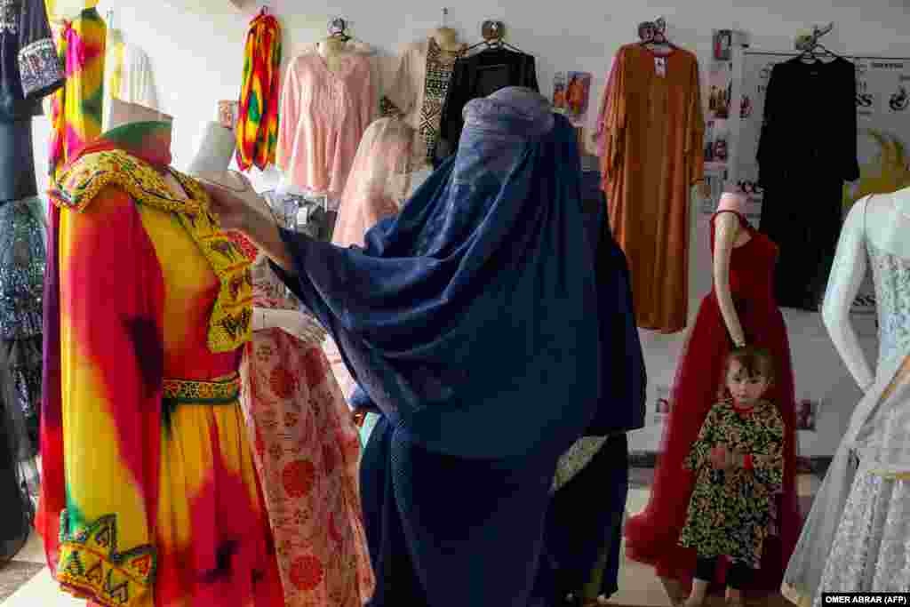 A burqa-clad Afghan woman looks at a dress in a shop in the Fayzabad district of Badakhshan Province.