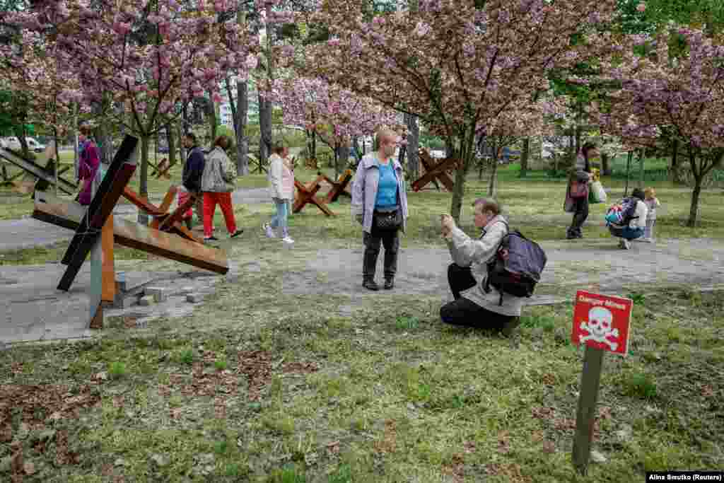 People take pictures under cherry blossoms in a park in Kyiv.&nbsp;