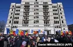 Демонстранты держат молдавские национальные флаги во время акции протеста, организованной молдавским депутатом от партии «Шор» в Кишинёве 12 марта