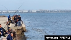 На набережной многолюдно: рыбаки выстроились в ряд. Стоят плотно, почти впритирку. Издалека видно, что клюет