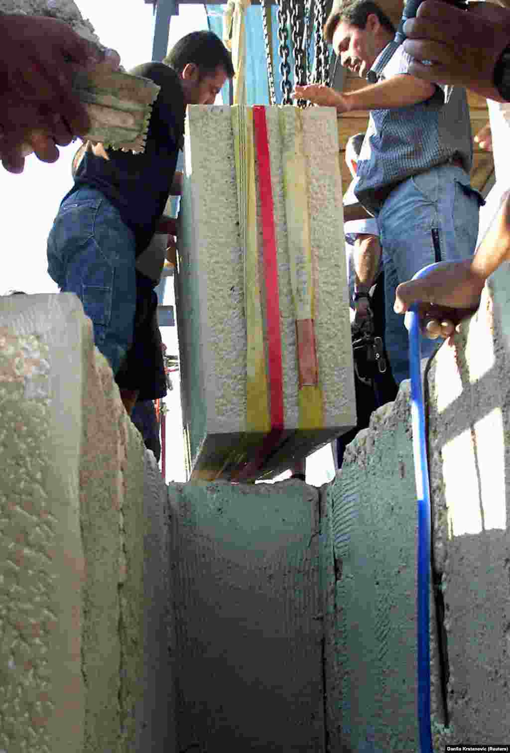 Engineers lower a keystone into place during reconstruction of the Mostar Bridge in August 2003. UNESCO provided technical oversight of the rebuilding project, which used stone from the same local quarry that Ottoman builders chose more than 400 years earlier. The limestone is white when freshly cut, but fades to grey over time.&nbsp;&nbsp; &nbsp;