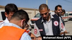 Paramedicii palestinieni verifică documentele de călătorie ale unei persoane care așteaptă să treacă în Egipt, la punctul de trecere a frontierei Rafah din sudul Fâșiei Gaza, 1 noiembrie 2023.