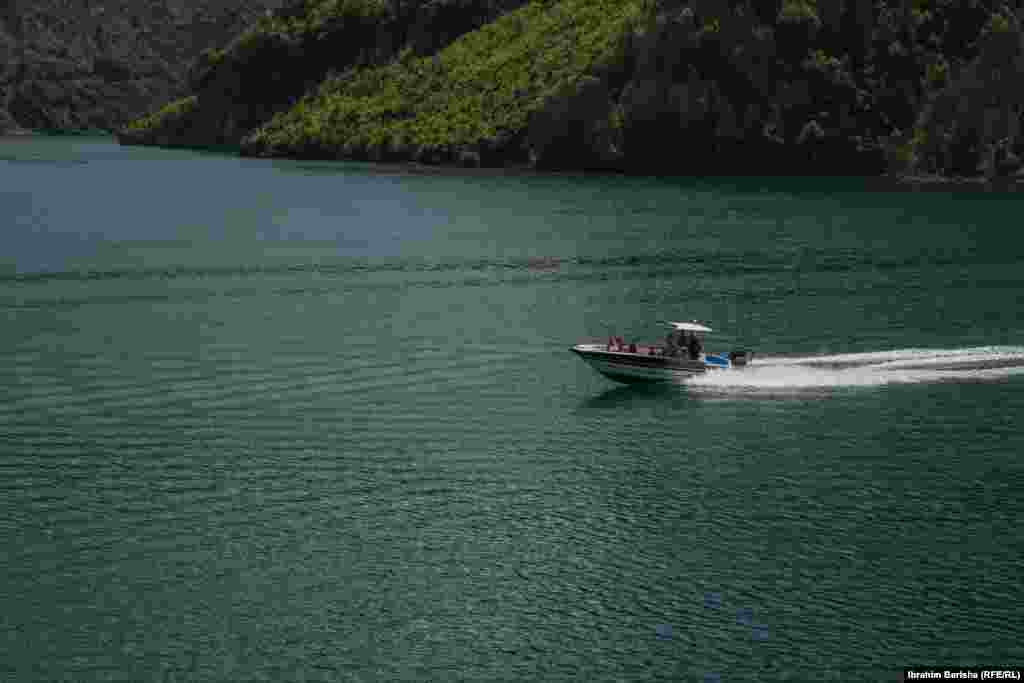 Një varkë me turistë në ujërat e liqenit.