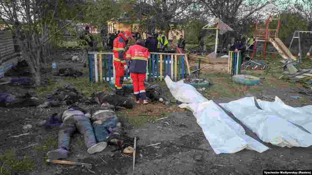 The bodies of victims lie scattered around a children&#39;s playground as firefighters and rescue workers survey the scene.