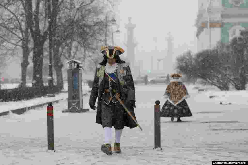 Street actors walk during a snowfall in St. Petersburg.