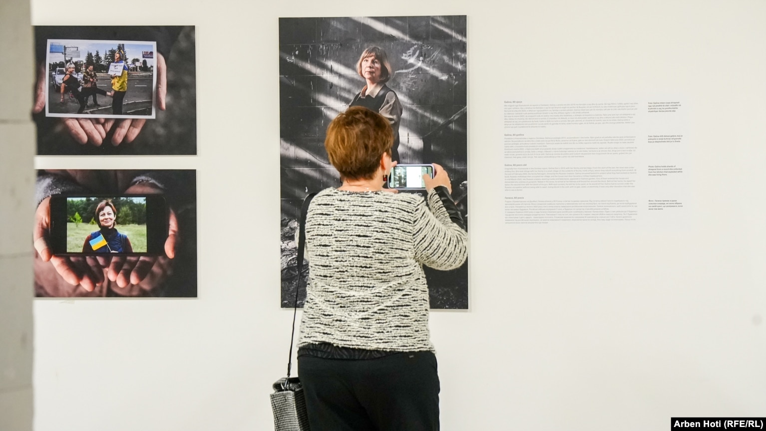 Një grua fotografon një nga punimet e paraqitura në ekspozitën "Ukraina: Një krim lufte". Përshkrimi i secilës fotografi të paraqitur në ekspozitë ishte në gjuhën shqipe, serbe, angleze dhe ukrainase.