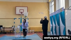 Избирательница фотографируется возле урны на участке в Уральске в день выборов в мажилис и маслихаты. 19 марта 2023 года