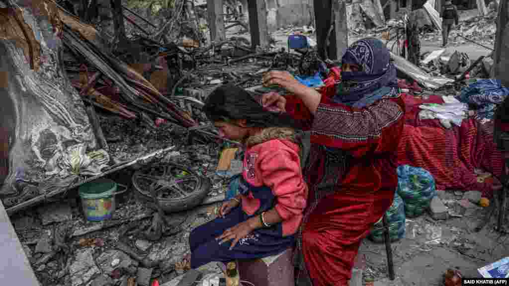 Egy palesztin nő lánya haját fésüli a tűzszünetben, 2023. november 27-én Hán Júnisz mellett. Több palesztin család visszatért az izraeli csapások alatt lerombolt otthonába, hogy összeszedje maradék épen maradt holmiját