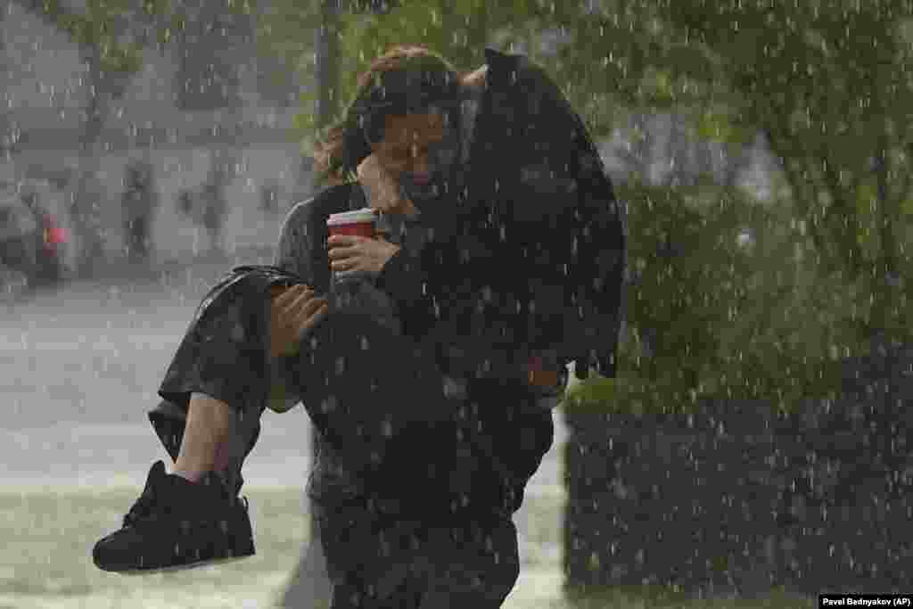 A man carries a woman during a heavy rain in Moscow.