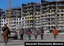 Работники из России на фоне новых домов в Мариуполе. Украина. 10 февраля 2023 года