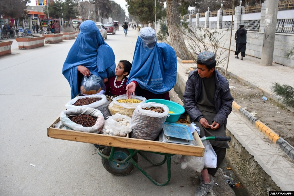 Women in burqas buy dry fruit on a street in the northern Faryab Province.