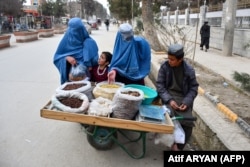 Women in burqas buy dry fruit on a street in the northern Faryab Province.