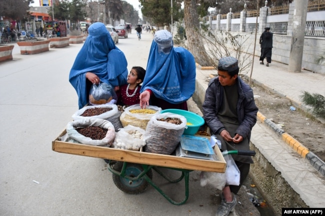Gratë e mbuluara me burka duke blerë fruta të thata në një rrugë në provincën Faryab, 10 mars 2024.