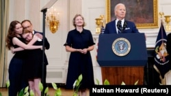 Kurmasheva's husband, Pavel Butorin, and daughters, Bibi and Miriam (left), embrace as U.S. President Joe Biden speaks about the release of Americans detained in Russia at the White House in Washington on August 1.