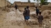 People walk near their damaged homes after heavy flooding in Baghlan Province in northern Afghanistan on May 11. 