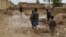 People walk near their damaged homes after heavy flooding in Baghlan Province in northern Afghanistan on May 11. 