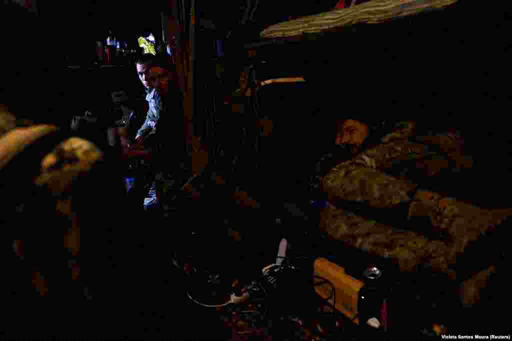 As the sounds of artillery rumble above, Ukrainian soldiers rest in their dugout.