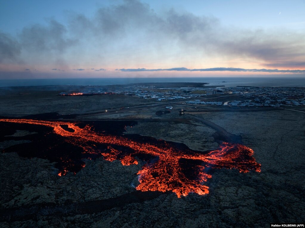 Shpërthimet e lavës dhe tymi i zi shihen afër shtëpive të banimit në qytezën jugperëndimore islandeze, Grindavik, pas shpërthimit të një vullkani, më 14 janar 2024.