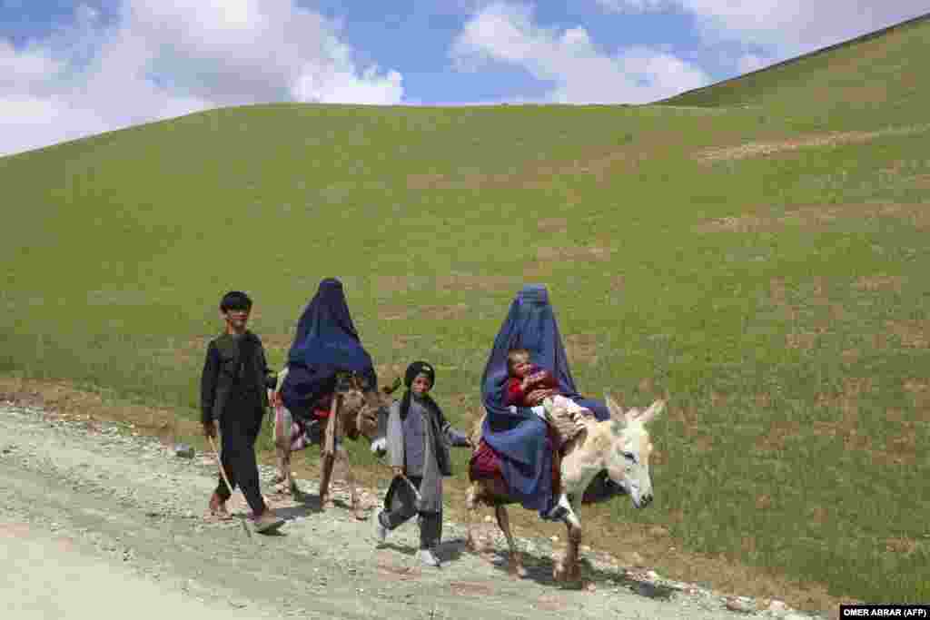 Burqa-clad Afghan women ride donkeys alongside children on a road near the village of Shah Mari in the Argo district of the remote Badakhshan Province.