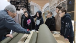 Школьники на уроках труда режут на станке ткань для маскировочных сетей. Россия, архивное фото