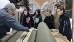 Школьники на уроках труда режут на станке ткань для маскировочных сетей. Россия, архивное фото