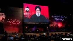 Supporters listen to the speech of Hizballah leader Sayyed Hassan Nasrallah on a video screen in Beirut on August 6.